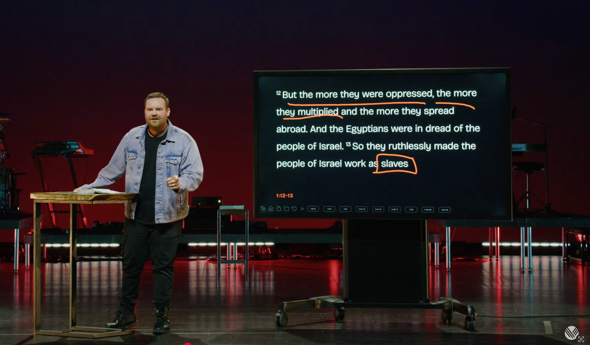 Pastor preaching from Exodus 1 with live orange markup on a HapGraph touchscreen